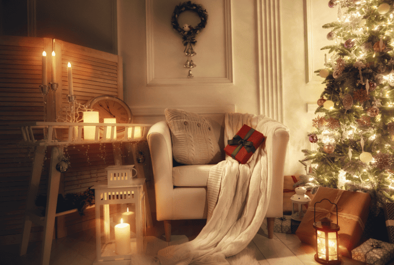 Home decorated for the holidays. Featuring a small sofa next to a lit Christmas tree with candles and soft lighting.